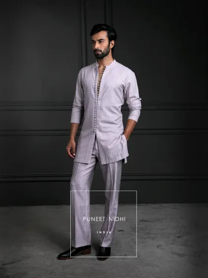 A blush pink longline kurta, tailored to perfection with a straight cut. Adorned with looped fabric buttons and a regal mandarin collar, it has heritage in its soul.