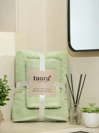 A set of light green towels, styled neatly for a catalogue or website. The focus is on the product's texture and neat presentation.