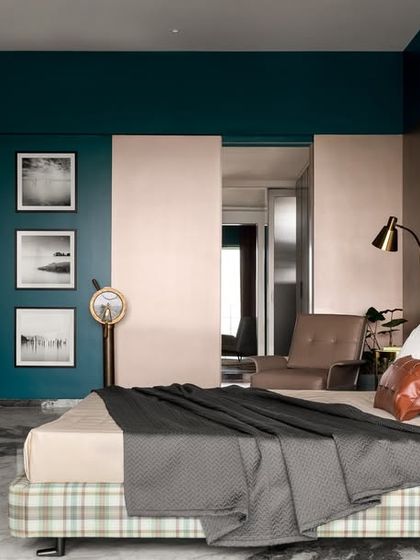 A wider view of the teal-toned bedroom, showing the spacious layout and the cozy reading chair. The combination of teal walls and a metallic accent wall adds a shimmering, elegant touch.