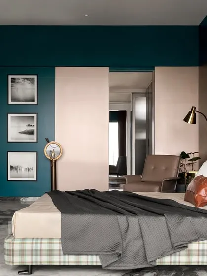 A wider view of the teal-toned bedroom, showing the spacious layout and the cozy reading chair. The combination of teal walls and a metallic accent wall adds a shimmering, elegant touch.