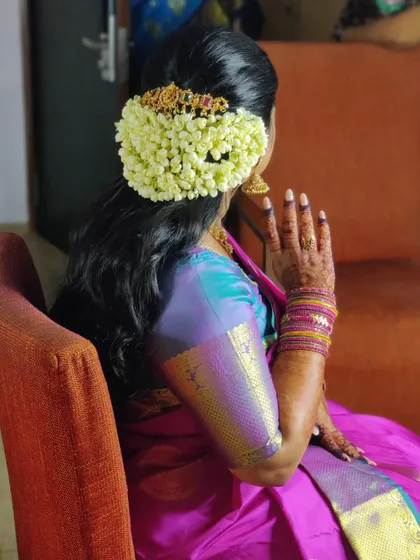 A view of the traditional South Indian bridal hairstyle, featuring a beautiful bun adorned with fresh jasmine and temple style hair jewelry.