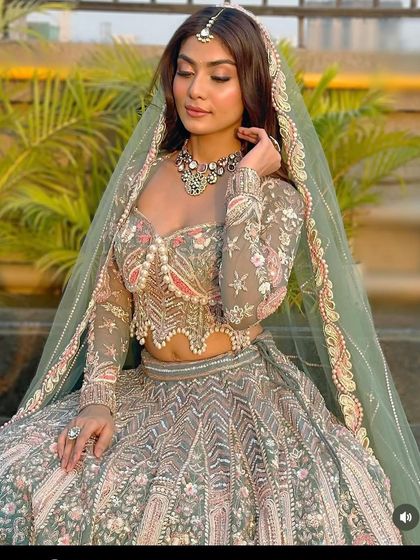 This pastel green lehenga with a pearl-encrusted blouse is a stunning choice for a daytime event or an evening reception. The sheer sleeves and detailed embroidery add a touch of modern sophistication.