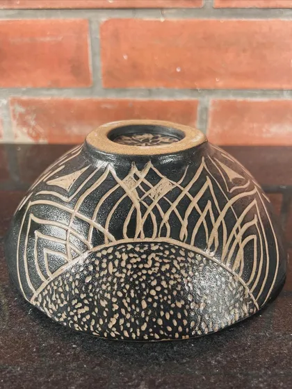 A stunning bowl with intricate sgraffito carving. The contrast between the black glaze and the raw clay body is so effective.