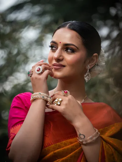 A three-quarter portrait focusing on the model's expression and the way she is adorned with multiple rings and bracelets.