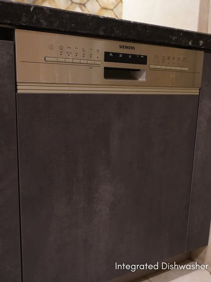 An integrated Siemens dishwasher in Esha Bahl's Delhi kitchen. The appliance is hidden behind a cabinet front, maintaining the seamless look of the Meteor Oxide Laminate finish.