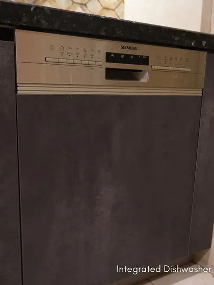 An integrated Siemens dishwasher in Esha Bahl's Delhi kitchen. The appliance is hidden behind a cabinet front, maintaining the seamless look of the Meteor Oxide Laminate finish.