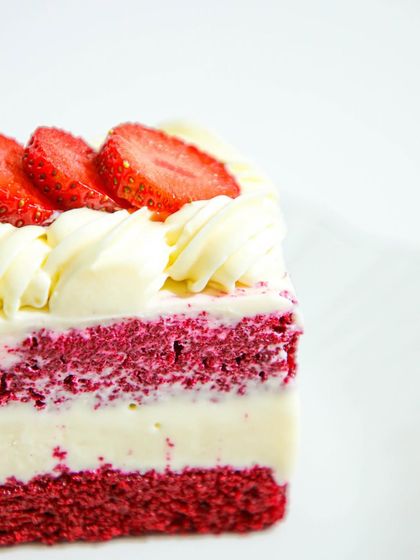 A close-up of a slice of our Red Velvet and Strawberry cake, showcasing its moist crumb and creamy layers.