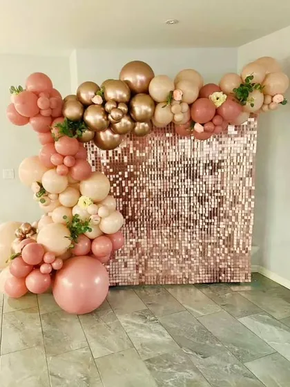A beautiful rose gold shimmer wall decorated with a cascade of matching balloons. This kind of backdrop rental is perfect for creating a stunning photo booth at any celebration.