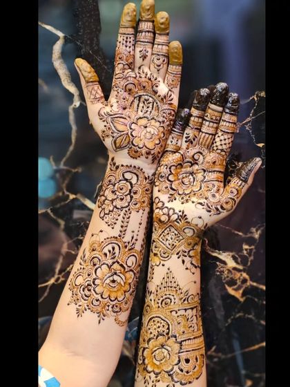 A beautiful example of designer mehendi where different patterns come together. One hand features a flowing floral design, while the other has more geometric and traditional Indian elements, creating a unique, asymmetrical look.