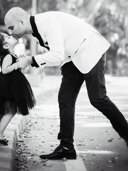 A timeless black and white photo capturing a tender moment between a father and his little girl. The gentle kiss on her forehead tells a story of protection and love. This image freezes a fleeting moment of connection that they will cherish forever.