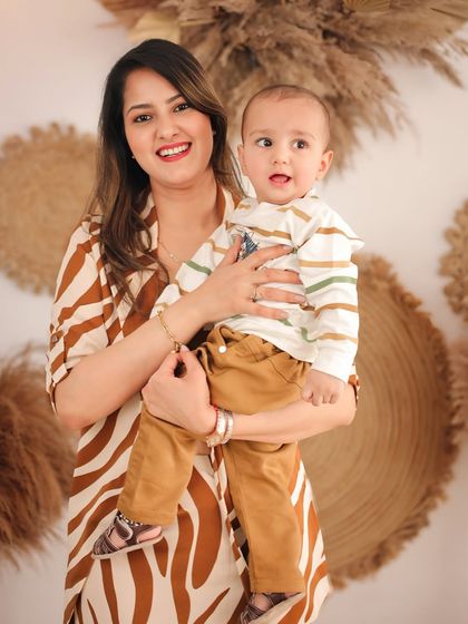 A beautiful portrait of a mother holding her curious baby boy. Both are looking towards the camera, creating a classic shot within our modern, boho-inspired studio setup.
