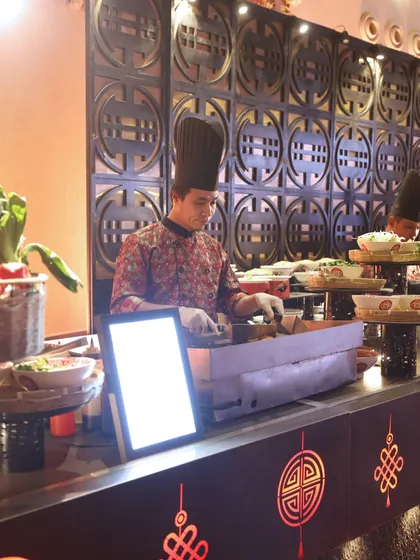 A chef at our live teppanyaki station, expertly grilling ingredients in front of guests. The sights and sounds are as much a part of the experience as the taste.