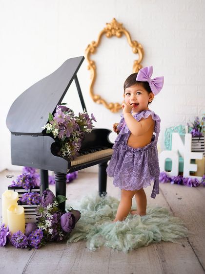 A little musician in the making! Posing by a miniature grand piano in this creative, purple-themed shoot.