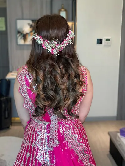 The back view of this floral mehendi hairstyle. The combination of the braid, the curls, and the fresh flowers is absolutely beautiful.