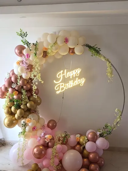 A sophisticated birthday decoration featuring a metal ring arch. I decorated it with a mix of rose gold, pastel, and white balloons, and added artificial flowers and greenery for a soft, botanical feel.
