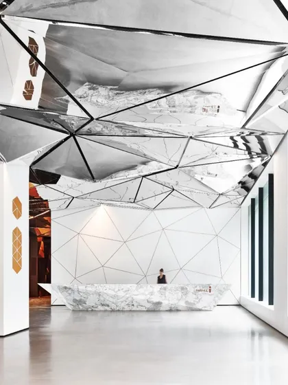 The main reception area, where the monolithic marble desk and reflective ceiling create a powerful first impression. The design is a statement of modern luxury and innovative spatial design.