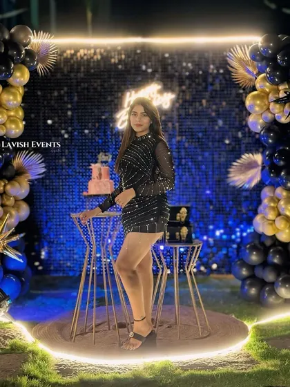 The birthday girl looking glamorous in front of her black and gold sequin party backdrop.