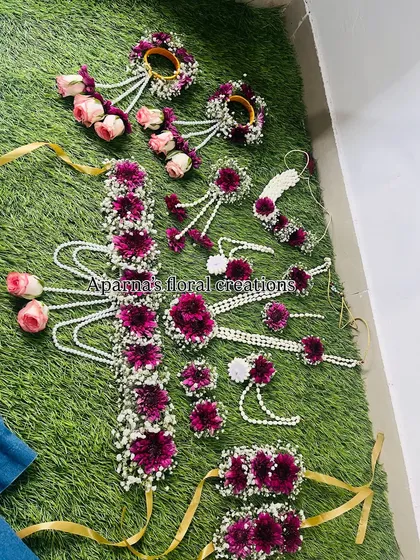 A grand floral set for a Haldi or baby shower. This design features deep magenta flowers, pink roses, and baby's breath, and includes a beautiful floral belt.
