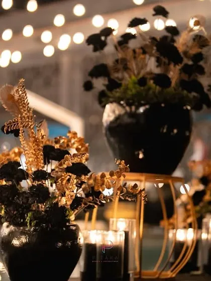 For a dramatic and moody look, we used black florals with gold accents, arranged in sleek black vases. The warm glow of the black candles under a canopy of string lights completed the sophisticated vibe.