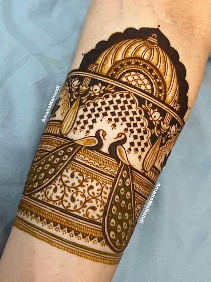 A close-up of the top portion of an arm band, featuring two peacocks in a decorative jharokha. The fine lines and patterns are a testament to skilled artistry.