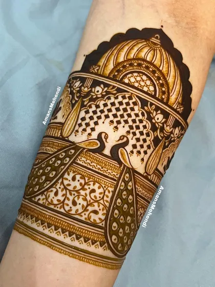 A close-up of the top portion of an arm band, featuring two peacocks in a decorative jharokha. The fine lines and patterns are a testament to skilled artistry.