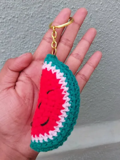 A juicy-looking crochet watermelon slice keychain. It's a fun and summery accessory for your keys or bag.