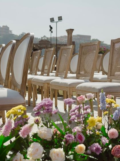 The elegant guest seating arranged for the ceremony. The clean lines of the chairs contrast beautifully with the organic, lush floral arrangements lining the aisle.