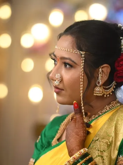 A side profile of the bride, highlighting her elegant hairstyle with red roses and the intricate details of her mundavalya.