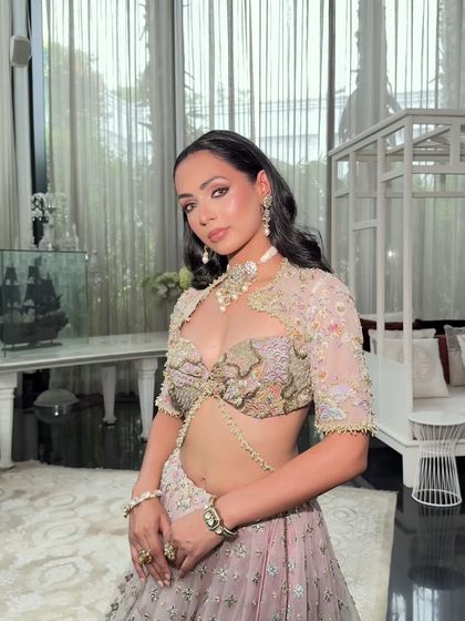 This front-facing portrait highlights the unique blouse design with a sheer, embroidered overlay and a delicate body chain, adding a touch of modern glamour.