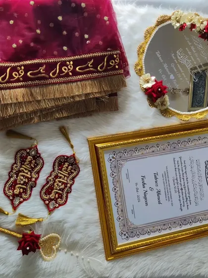 A different arrangement of the red and gold Nikah set. This view highlights the intricate embroidery on the Iman Zamin and the delicate floral work on the Muh Dikhaye mirror.