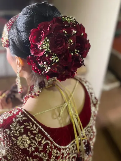 A bridal hairstyle needs to be beautiful from every angle. This classic bridal bun, decorated with fresh red roses and baby's breath, is a perfect example. It’s elegant, secure, and provides a perfect base for setting the dupatta.