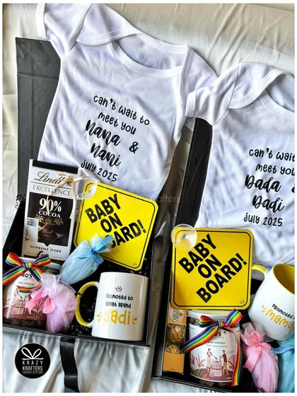 A full view of two distinct pregnancy announcement hampers, one for the 'Nana & Nani' and one for the 'Dada & Dadi', each with custom onesies and mugs.