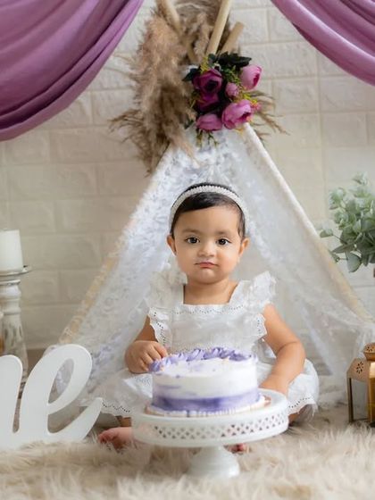 A quiet moment before the cake smash. This little girl looks so angelic in her white dress, ready to celebrate her first birthday.