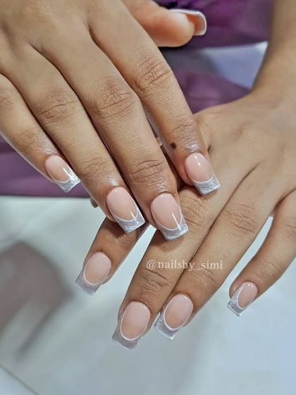 A stunning twist on a classic look. These are cat-eye French nails, where the tip is made with a reflective silver cat-eye polish.