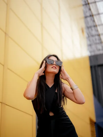 An upward-angle shot that gives the portrait a sense of power and drama. The yellow wall and the model's pose create a high-fashion, editorial feel.