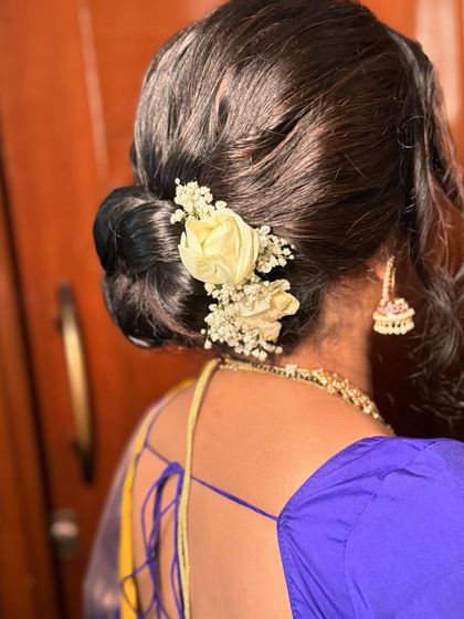 A close-up of the low bun, showing the delicate placement of the white roses. This style is perfect for a bride who appreciates understated elegance.
