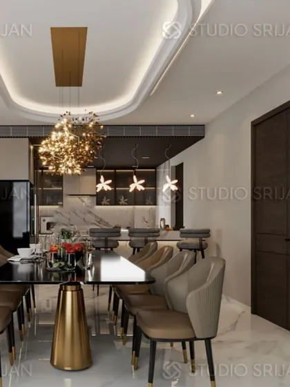 The dining area in the Krishna Park residence, featuring a dramatic, sparkling chandelier over a dark dining table, with an open-concept kitchen and bar in the background.