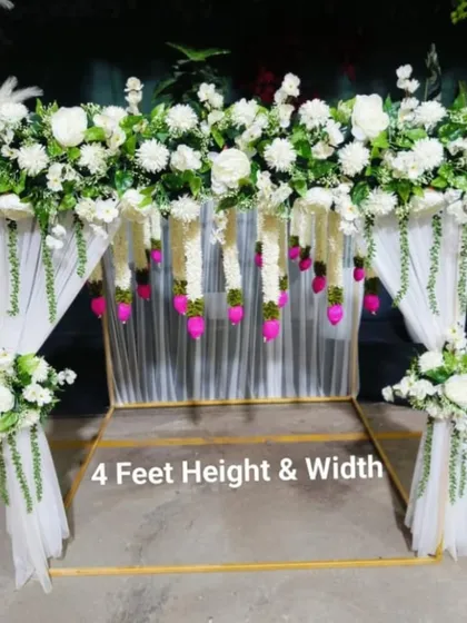 A 4x4 feet ready-to-book floral arch. This beautiful white setup with hanging tassels is perfect for framing a small mandap or creating an elegant photo corner for intimate gatherings.