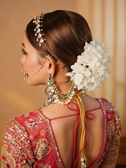 The hairstyle is just as important as the makeup. This detailed shot shows the neat floral bun that completes the timeless and classic 'Zehra' bridal look.