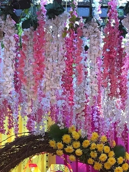 A beautiful detail shot of hanging wisteria flowers mixed with yellow marigolds. This type of floral ceiling installation can transform any space, adding texture and color from above.