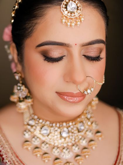 A beautiful close up of the bride's face. Her eyes are closed, highlighting her flawless bridal makeup, from the shimmering eyeshadow to the perfectly applied lipstick, and her stunning Polki jewelry.
