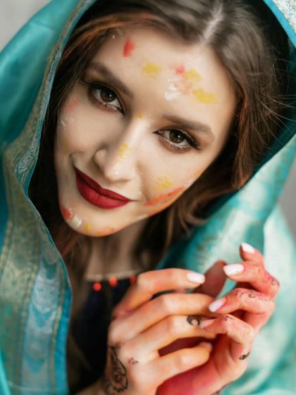 A beautiful portrait of a woman with her face gently dusted with Holi colors, her smile and gaze capturing the joyful spirit of the festival.