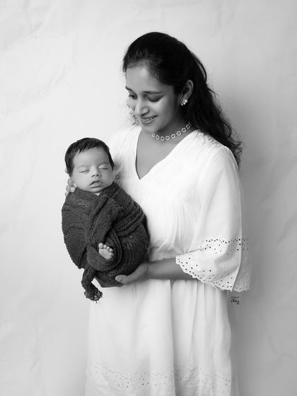 A mother holding her sleeping baby, converted to a soft black and white. This timeless style makes the emotional connection the central focus of the image.