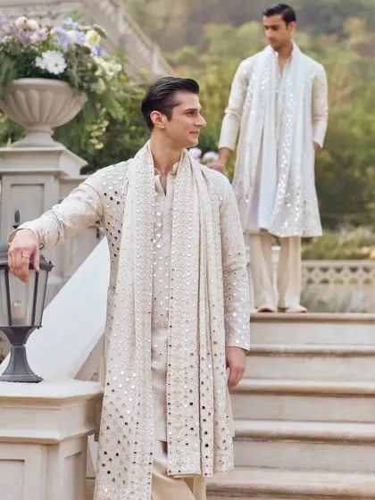 Two models on a staircase showcasing the elegance of the ivory mirror-work kurta sets.