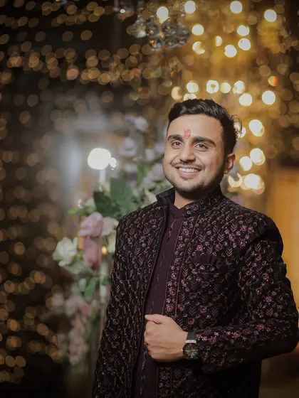 A classic portrait of the groom, Saurabh, at his engagement ceremony. The bokeh from the fairy lights in the background adds a magical touch to the photograph.