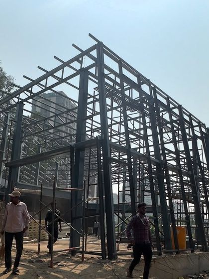 The bare steel frame of the Experience Center, showcasing the building's structural grid against the sky.