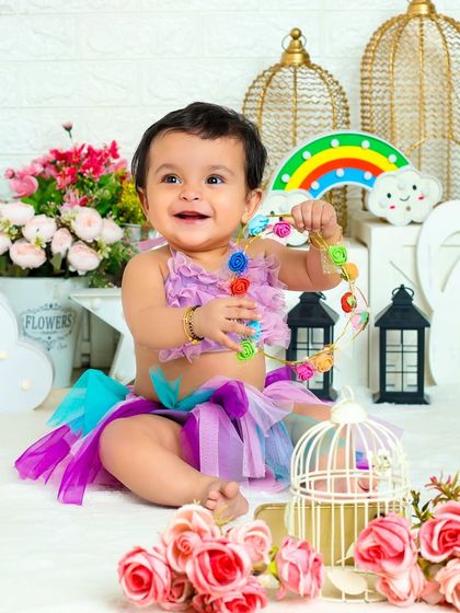 This little girl in a colorful tutu is playing with a string of flowers, her happy expression lighting up the frame.