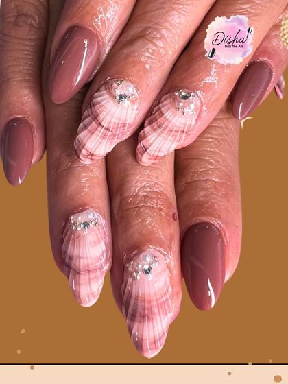 Giving you full beach vibes with these 3D seashell nails. The textured shells are paired with a solid mauve polish and accented with tiny pearls for a unique, ocean-inspired look.