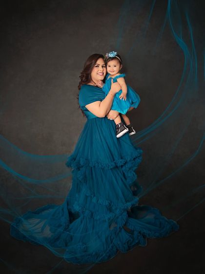 A mother and daughter portrait that feels like a fairytale. The flowing teal gown and artistic light effects create a magical atmosphere around this beautiful duo.