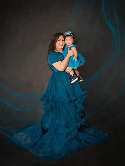 A mother and daughter portrait that feels like a fairytale. The flowing teal gown and artistic light effects create a magical atmosphere around this beautiful duo.